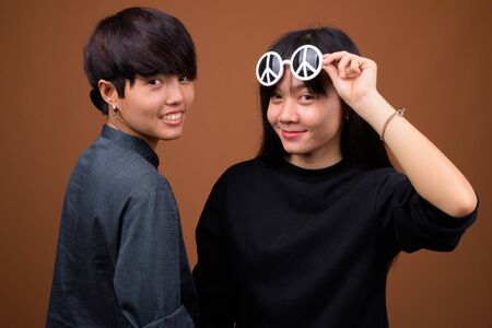 Young Asian lesbian couple together and in love against brown ba