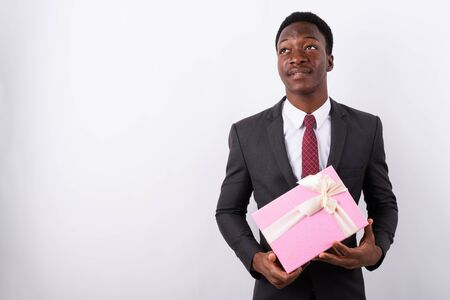Young handsome African businessman holding gift box against whitの写真素材