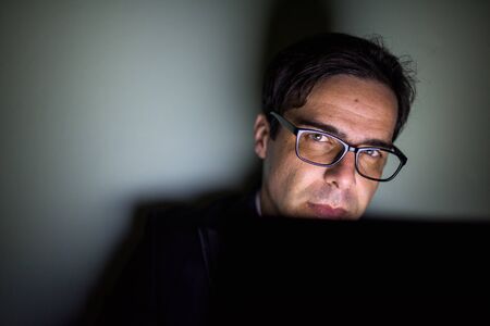 Handsome Persian businessman using laptop in dark room