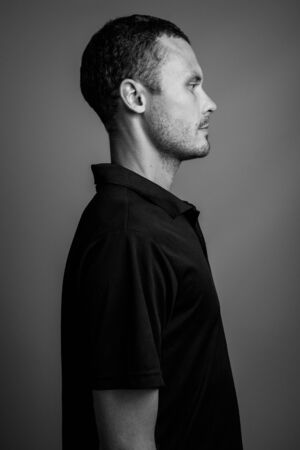 Handsome man against gray background in black and whiteの写真素材