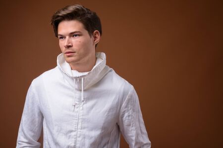 Studio shot of young handsome man against brown backgroundの写真素材