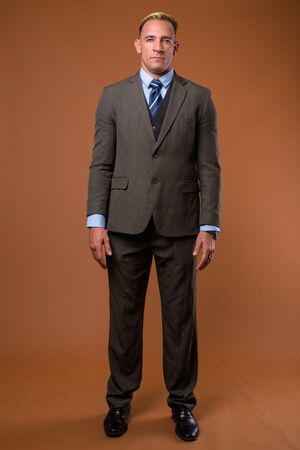 Full body shot of businessman standing against brown backgroundの写真素材
