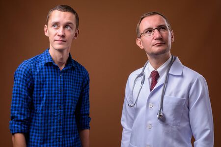 Man doctor and young man patient against brown backgroundの写真素材