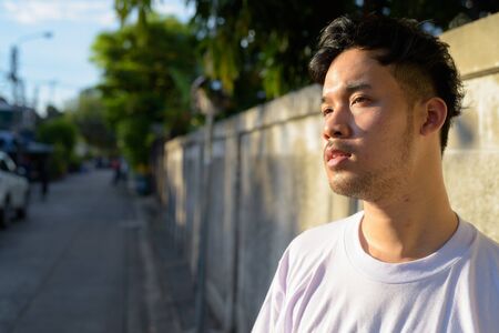 Young Asian man relaxing in the streets outdoorsの写真素材