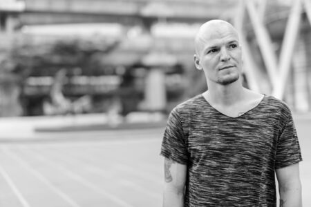 Young handsome bald man thinking in the city streets outdoorsの写真素材