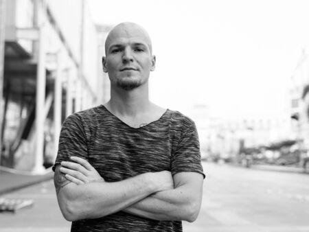 Young handsome bald man with arms crossed outside of the mall in the cityの写真素材