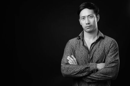 Young handsome Asian businessman against black background