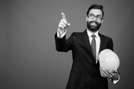 Young handsome bearded Persian businessman against gray backgroundの写真素材
