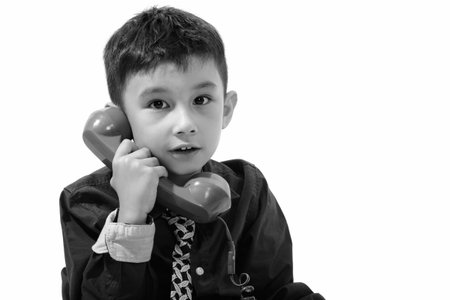 Studio shot of cute boy talking on old telephoneの写真素材