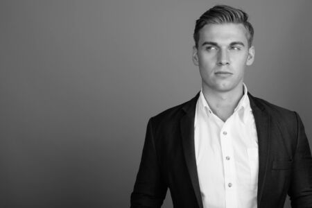 Face of young handsome businessman wearing suit in black and whiteの写真素材