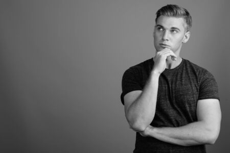 Portrait of young handsome man against gray background in black and whiteの写真素材