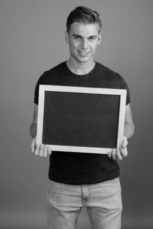 Portrait of young handsome man against gray background in black and whiteの写真素材