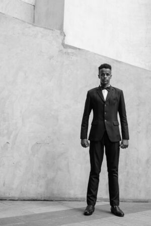 Young handsome African businessman wearing suit against concrete wall outdoorsの写真素材
