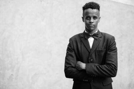Young handsome African businessman wearing suit against concrete wall outdoorsの写真素材