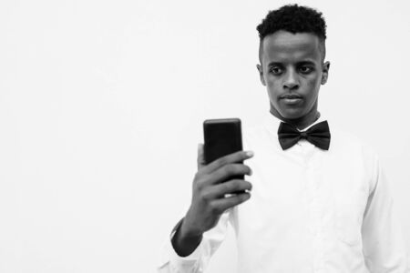 Young handsome African businessman using mobile phone against white backgroundの写真素材