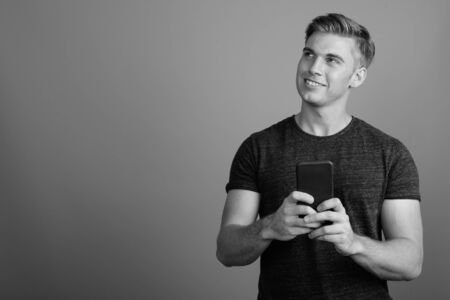 Portrait of young handsome man against gray background in black and whiteの写真素材