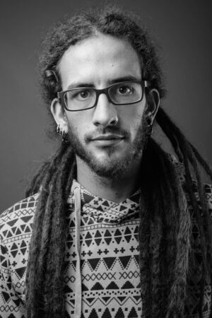 Young handsome Hispanic man with dreadlocks in black and white