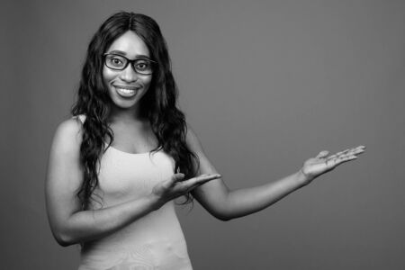 Young beautiful African woman wearing eyeglasses against gray backgroundの写真素材