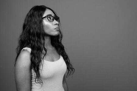 Young beautiful African woman wearing eyeglasses against gray backgroundの写真素材