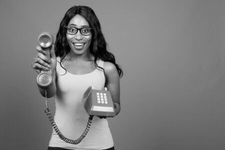 Young beautiful African woman wearing eyeglasses against gray backgroundの写真素材