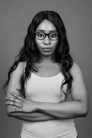 Young beautiful African woman wearing eyeglasses against gray backgroundの写真素材