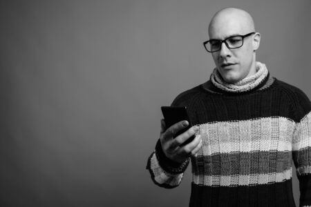 Handsome bald man against gray background in black and whiteの写真素材