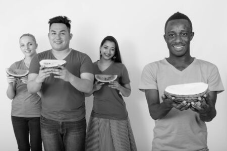 Happy young African man with diverse group of multi ethnic friends smiling while holding slice of...