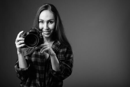 Studio shot of young beautiful hipster woman with camera in black and whiteの写真素材