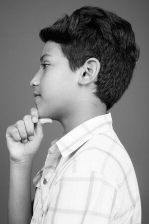 Young Indian boy wearing checkered shirt against gray backgroundの写真素材