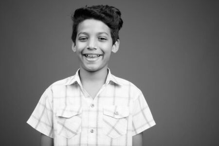 Young Indian boy wearing checkered shirt against gray backgroundの写真素材