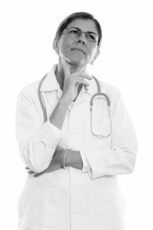 Studio shot of mature beautiful woman doctor thinking while looking upの写真素材