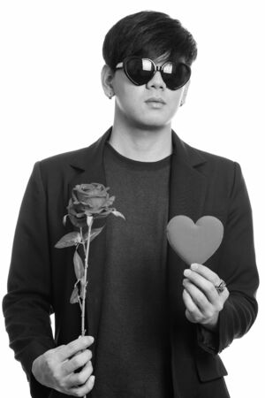 Cool handsome Asian businessman wearing heart shaped sunglasses while holding red roses and heartの写真素材