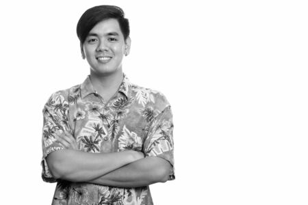 Young happy Asian tourist man smiling with arms crossed