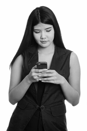 Studio shot of young Asian woman using mobile phoneの写真素材