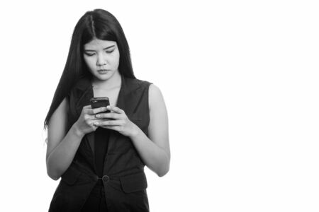 Studio shot of young Asian woman using mobile phoneの写真素材