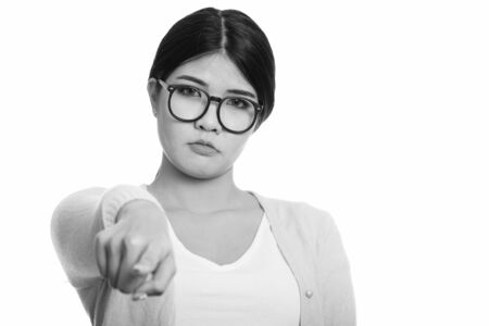 Studio shot of young Asian nerd woman pointing finger at cameraの写真素材