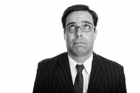 Close up of young Persian businessman thinking while looking up with eyeglasses isolated against white backgroundの写真素材