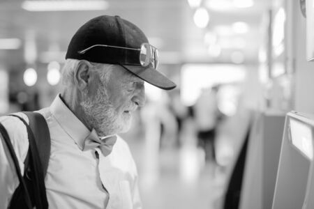 Handsome bearded senior tourist man exploring the city in black and whiteの写真素材