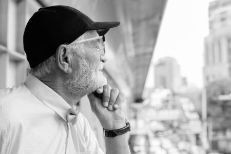 Handsome bearded senior tourist man exploring the city in black and white