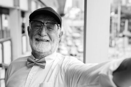 Handsome bearded senior tourist man exploring the city in black and whiteの写真素材