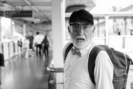 Handsome bearded senior tourist man exploring the city in black and whiteの写真素材
