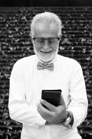 Handsome bearded senior tourist man exploring the city in black and whiteの写真素材