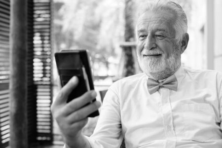 Handsome bearded senior tourist man exploring the city in black and whiteの写真素材