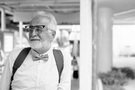 Handsome bearded senior tourist man exploring the city in black and whiteの写真素材