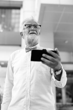 Handsome bearded senior tourist man exploring the city in black and whiteの写真素材