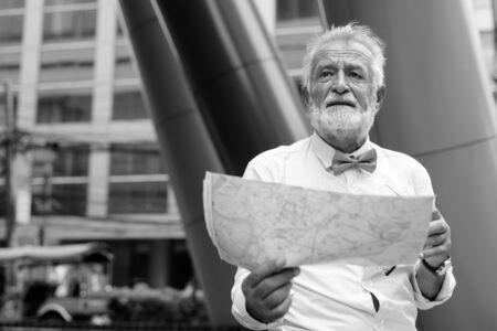Handsome bearded senior tourist man exploring the city in black and whiteの写真素材