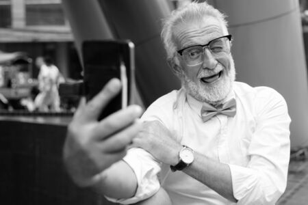 Handsome bearded senior tourist man exploring the city in black and whiteの写真素材