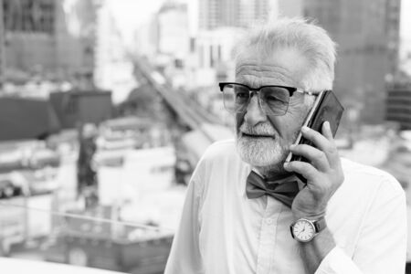 Handsome bearded senior tourist man exploring the city in black and whiteの写真素材