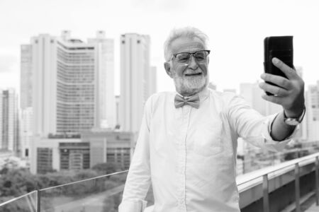 Handsome bearded senior tourist man exploring the city in black and whiteの写真素材