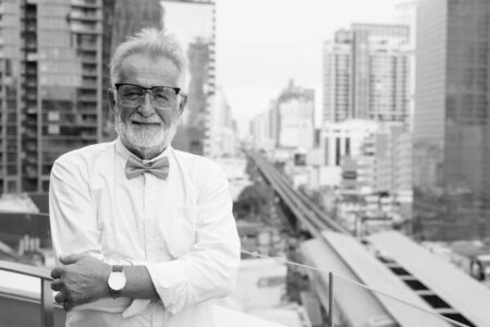 Handsome bearded senior tourist man exploring the city in black and whiteの写真素材